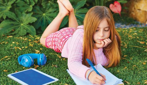 blond-kid-girl-homework-lying-grass-turf