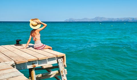 girl-with-hat-sitting-wooden-wharf